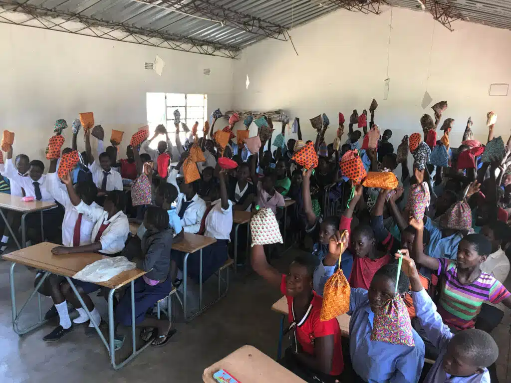 Happy schoolgirls holding their reusable sanitary pads in a classroom in Zambia