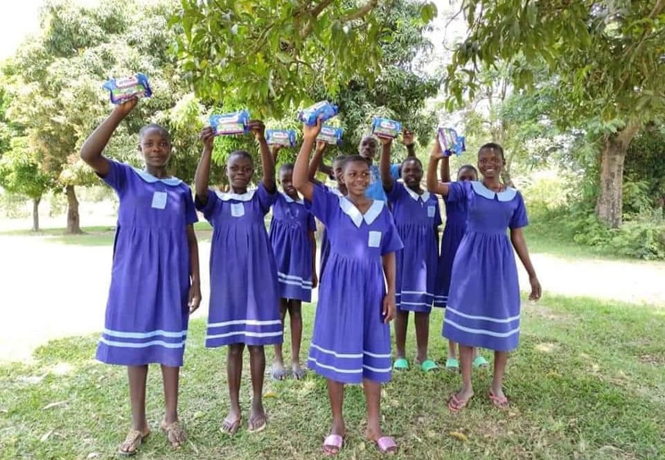 Schoolgirls holding AFRIpads Menstrual Kits